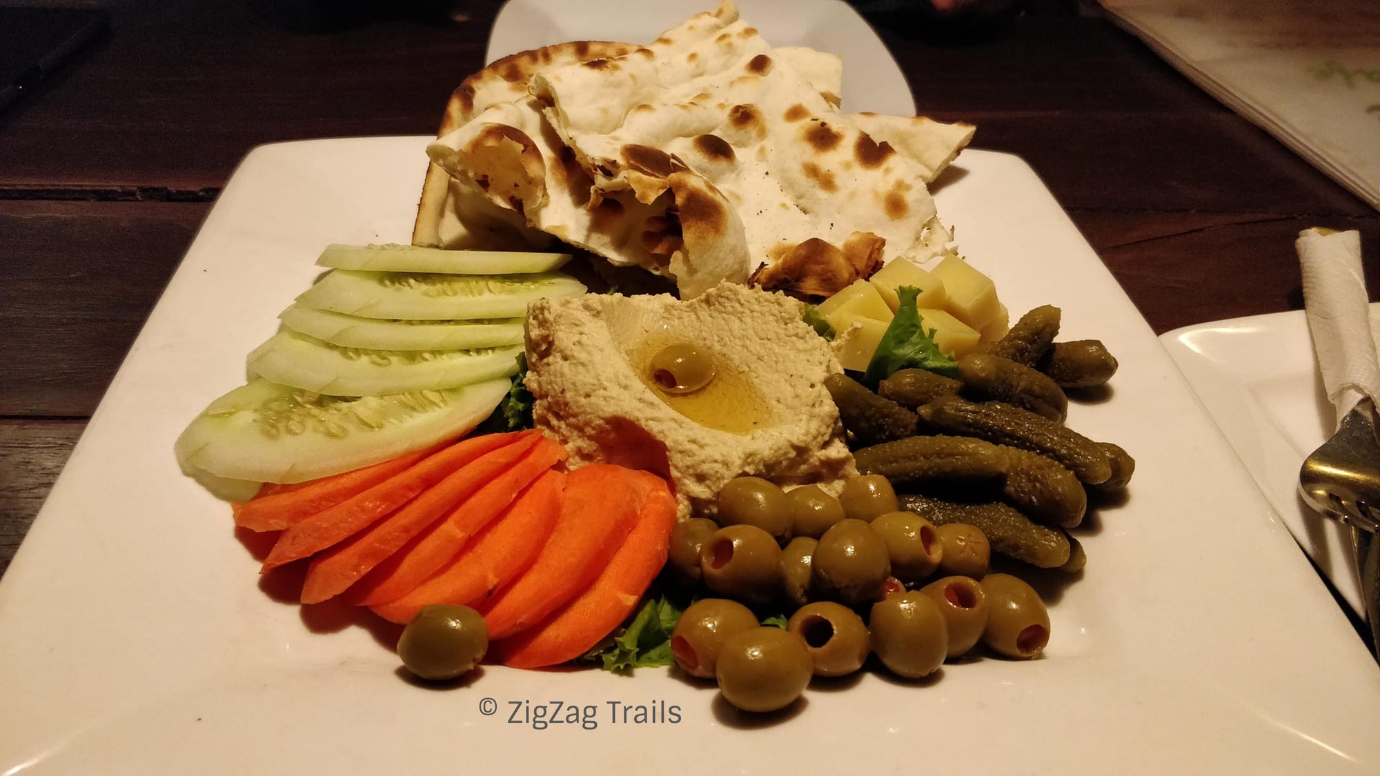Delicious veggie platter loaded with Pita Hummus, Salad, Olives and Pickled cucumber.