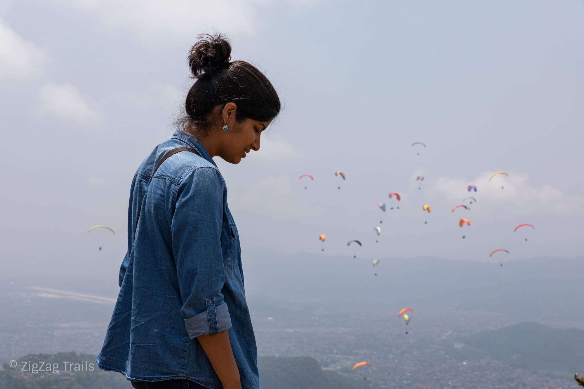 Many paragliders in the sky, colouring the color with neon color gliders.