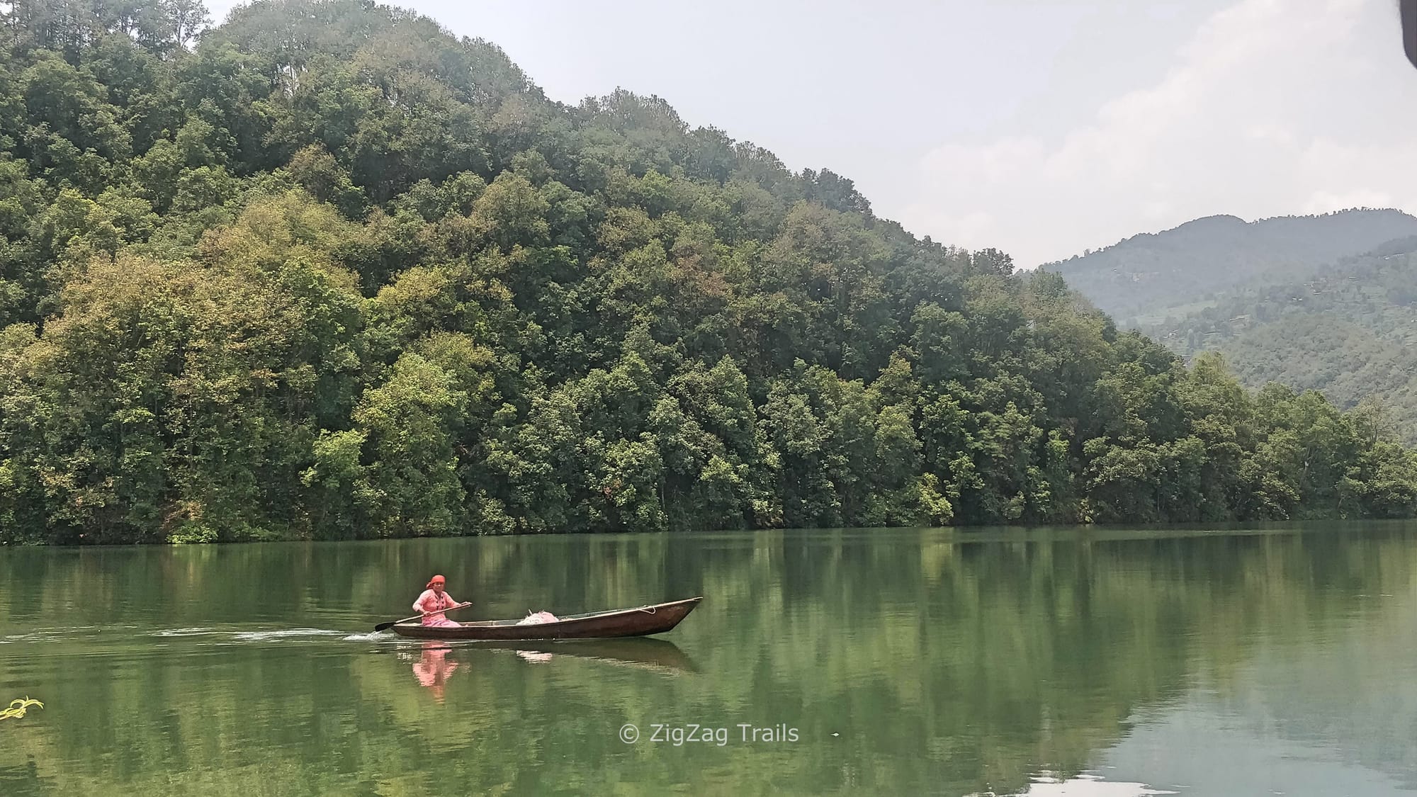 A woman rowing boat in tranquil water of Begnas Lake.